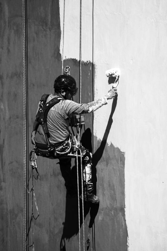 pexels-photo-34581863 A worker uses rope access to paint a building wall in Buenos Aires, highlighting industrial labor practices.