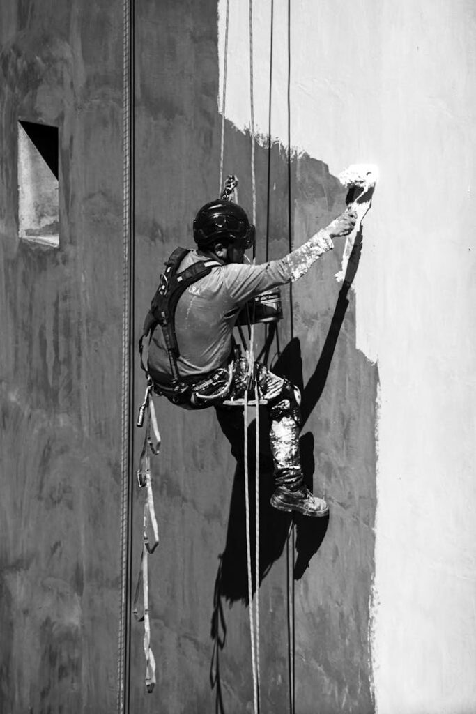 A worker paints a building facade using rope access in Buenos Aires, Argentina.